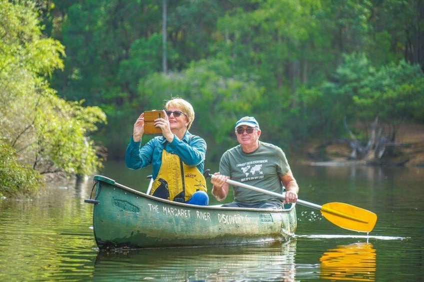 Two people in a green canoe on a river surrounded by trees. 3