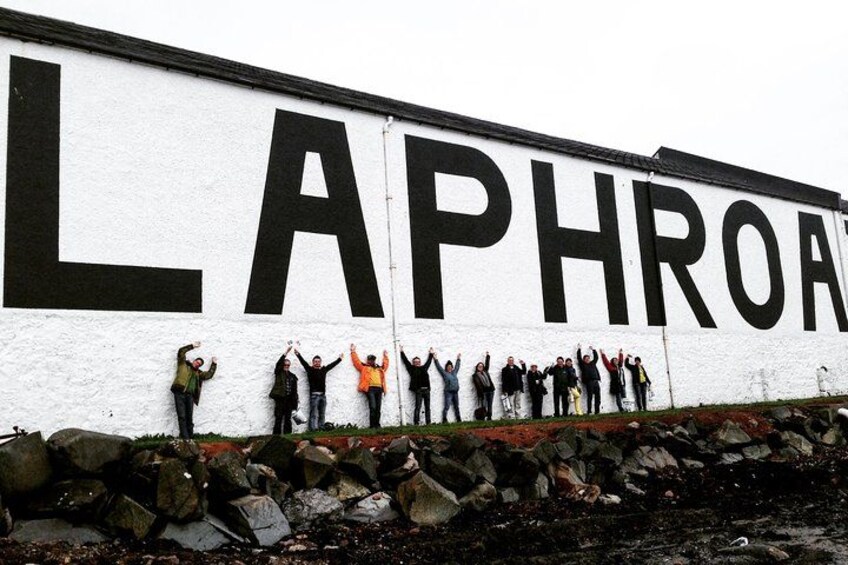 Un groupe de personnes se tient devant un grand mur sur lequel est peint le mot « LAPHROA ». 2