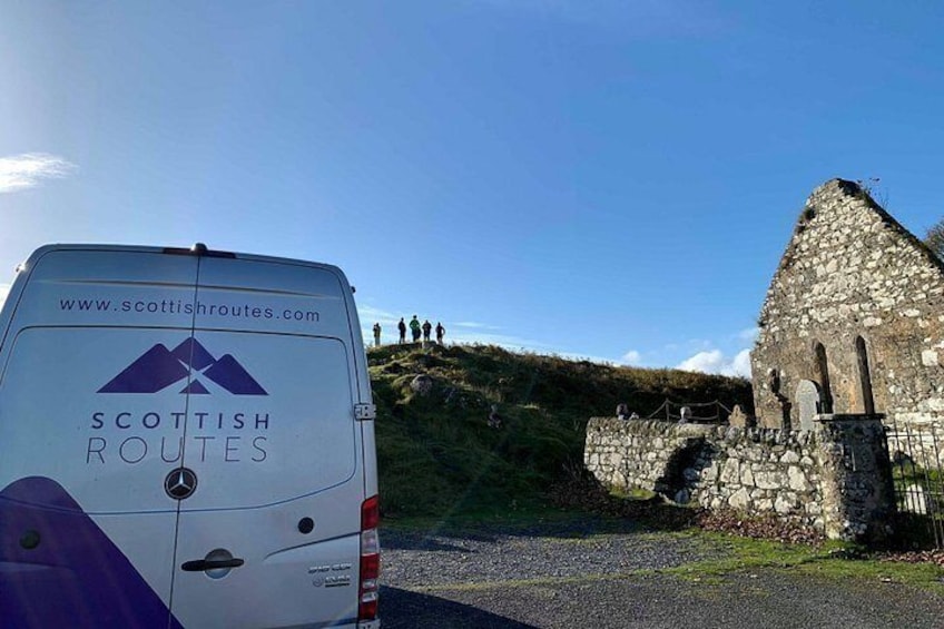 Un fourgon blanc arborant le logo « Scottish Routes » était stationné près d’une structure en pierre, et des personnes se trouvaient sur une colline. 5