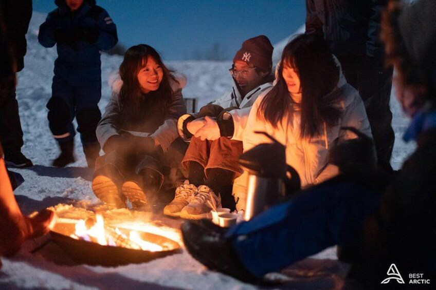 A group of people gathered around a campfire in a snowy outdoor setting. 4
