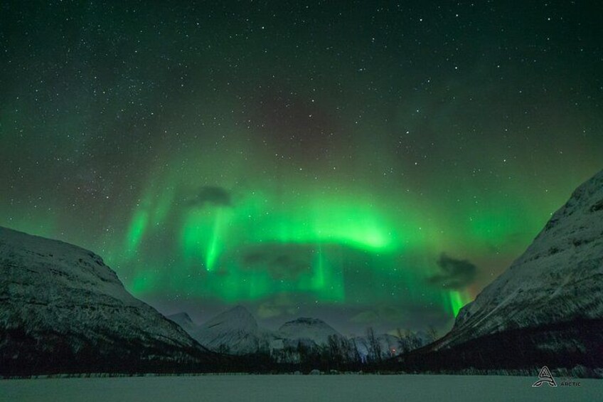 The Northern Lights over a snowy landscape with mountains. 3