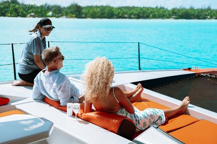 A boat with people relaxing on the deck, a clear blue sea, and a distant shoreline. 3