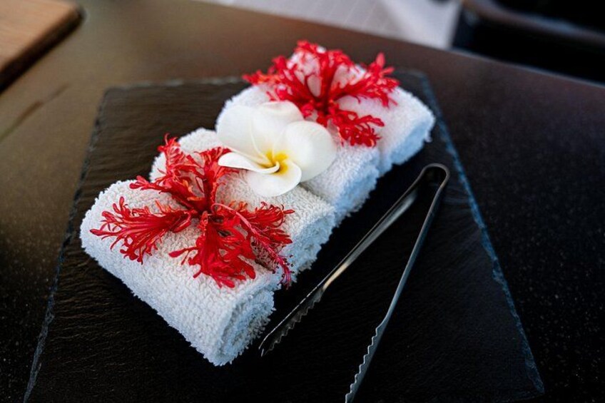 A towel with red flowers and a white flower on a black slate. 2