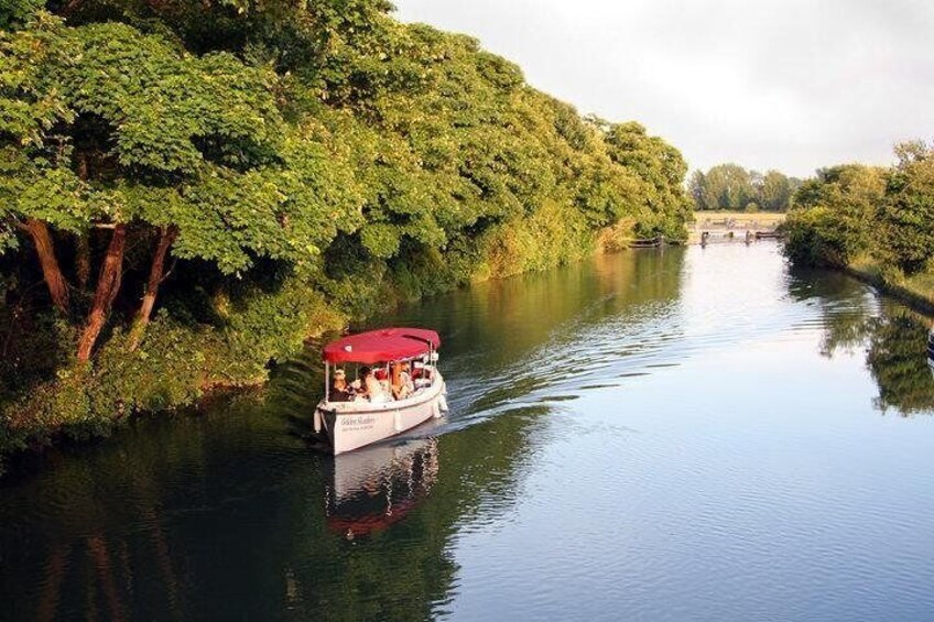 A boat with a red canopy on a calm river surrounded by lush greenery. 1