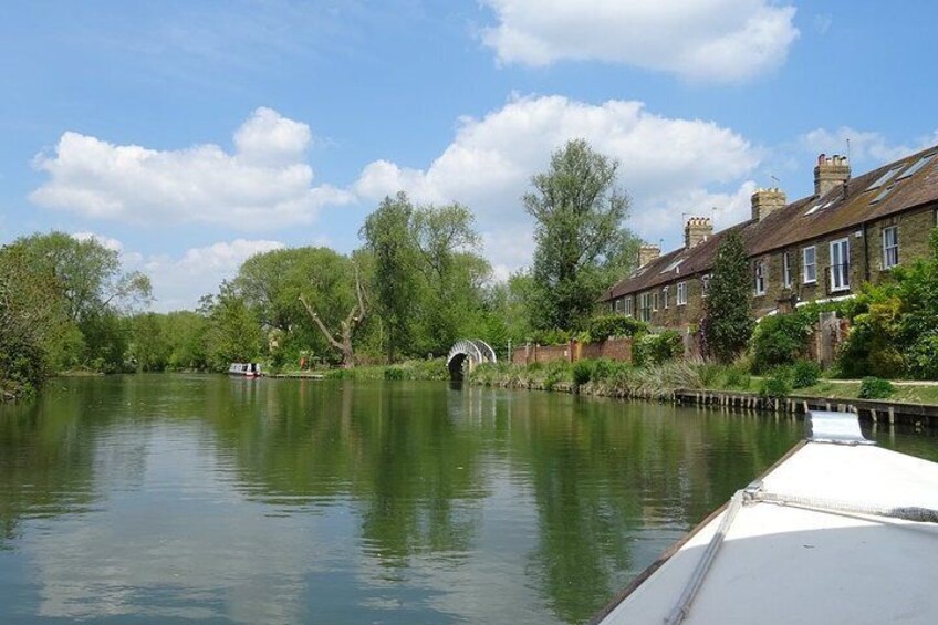A calm river with a bridge, lush greenery, and residential buildings along the banks. 3