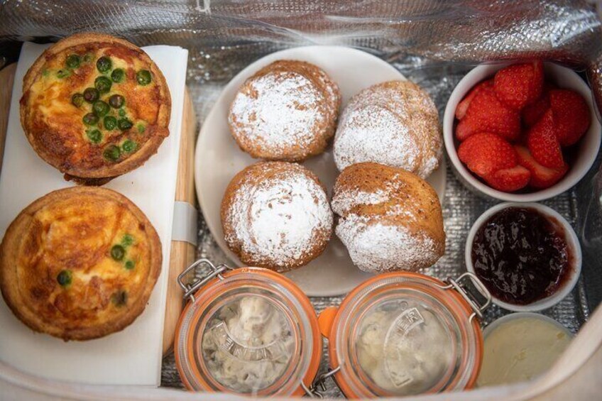 A variety of pastries including a quiche, cream puffs, and a strawberry dish, along with jars of cream and jam. 5