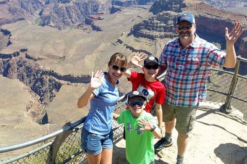 A group of people standing on a viewing platform with a canyon in the background. 1