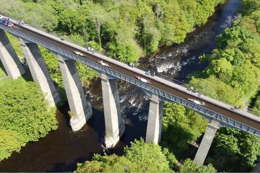 A bridge over a river with people walking and vehicles on it. 1