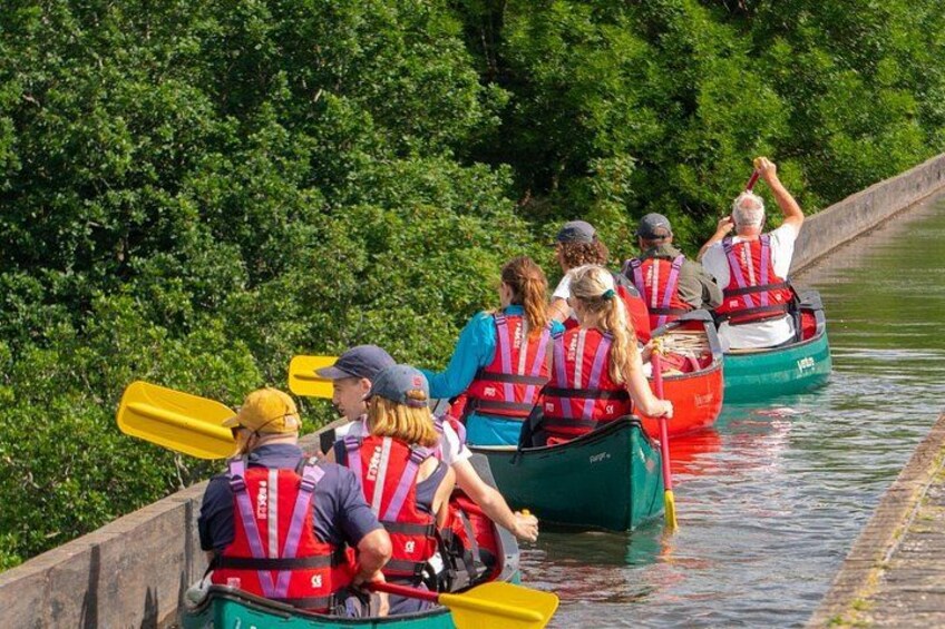 A group of people in canoes on a river, wearing life jackets. 2