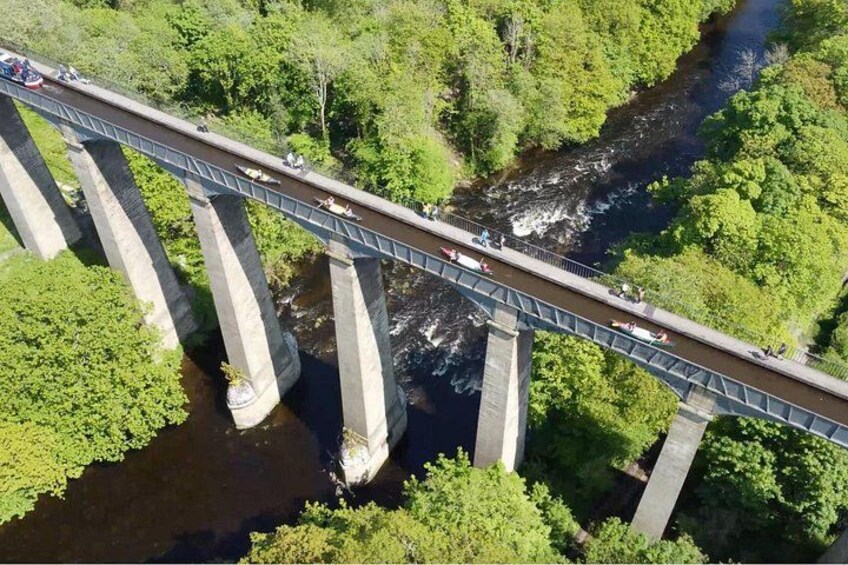 A bridge over a river with multiple supports and surrounded by greenery. 1
