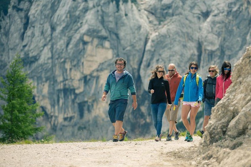 Un groupe de randonneurs sur un sentier de terre, avec des montagnes rocheuses en arrière-plan. 2