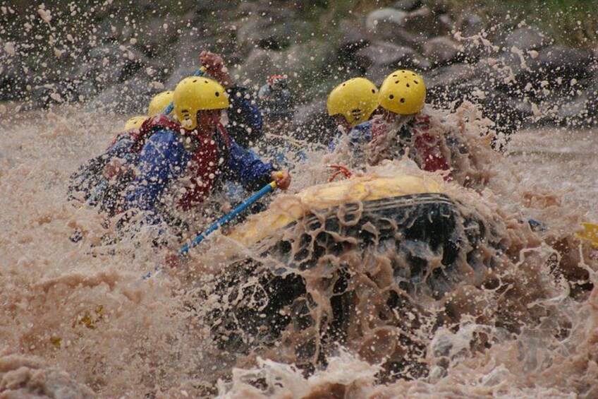 People in a white kayak navigating through a turbulent river. 2