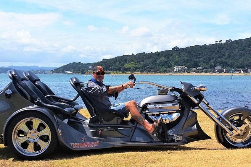 Un hombre sentado en una motocicleta con sidecar junto a un lago. 3