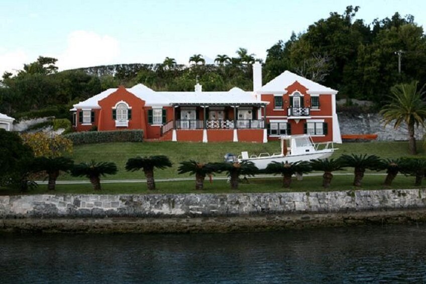 A red house with a white roof, a boat, and palm trees. 1