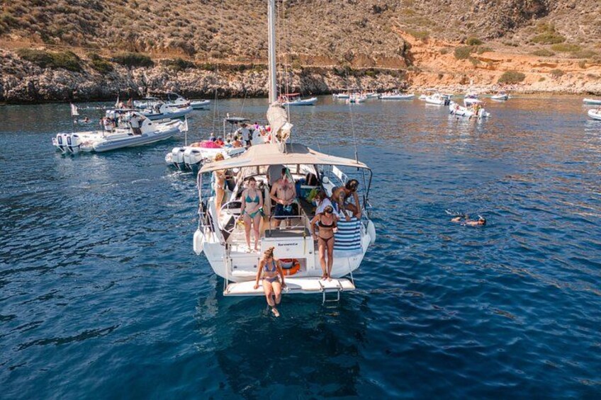 Un velero con gente en la cubierta, rodeado de aguas tranquilas y otros barcos. 4