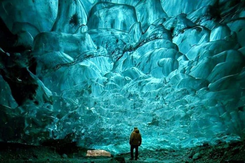 Una persona de pie en una cueva con formaciones de hielo. 2
