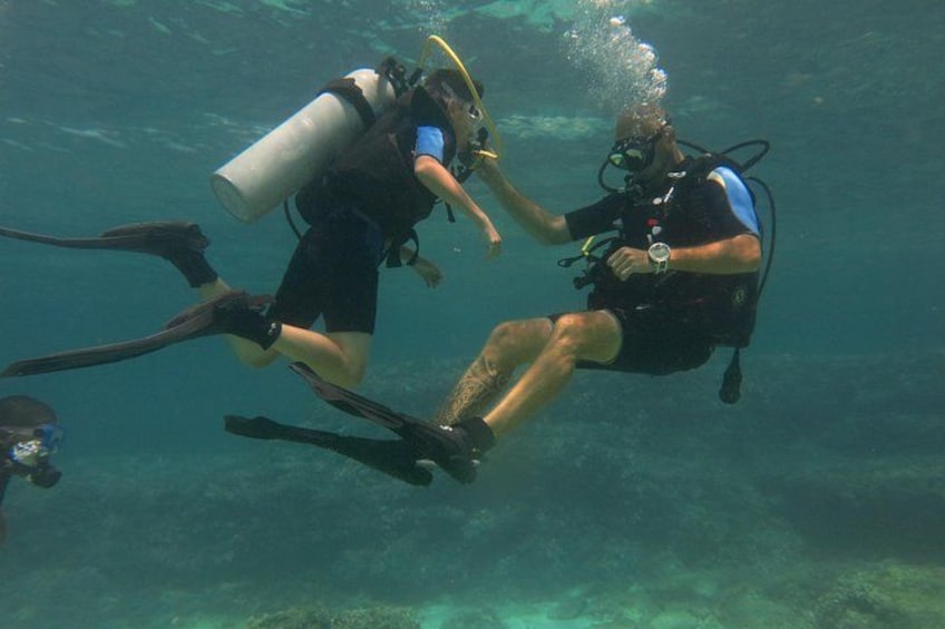 Zwei Taucher unter Wasser, einer mit einem großen Sauerstofftank und der andere mit einem kleineren. 1