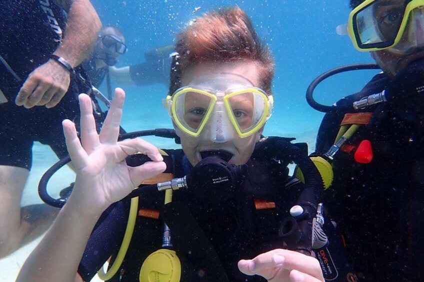 Eine Person mit Tauchausrüstung unter Wasser, die eine Handbewegung macht. 4