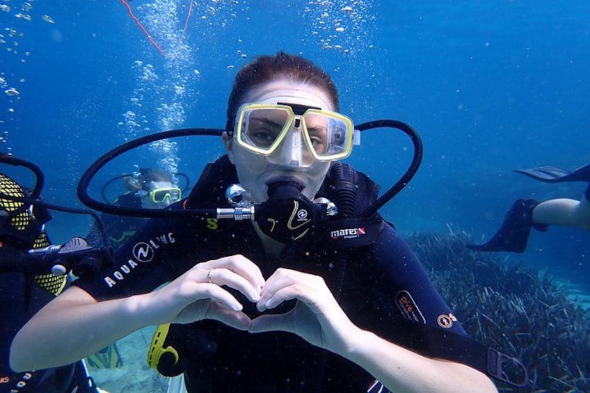 Ein Taucher unter Wasser mit Atemregler und Tauchtank, umgeben von Meereslebewesen. 2