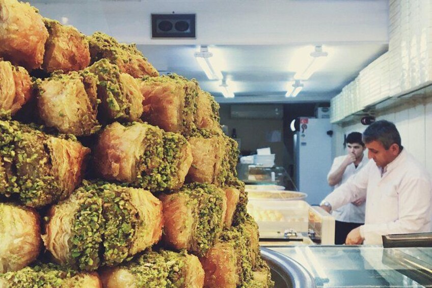 A stack of pastries with a green topping, likely pistachio, in a kitchen setting. 3