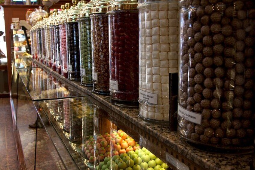 Une variété de fruits et de noix confits, présentés dans des bocaux en verre, sur une étagère. 1