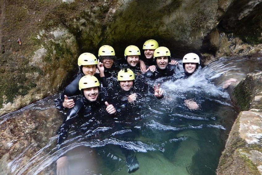 A group of people in a water-filled cave with helmets, surrounded by rocky walls. 4