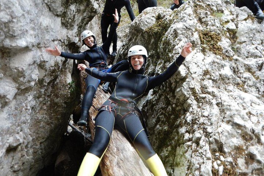Two people in wetsuits climbing a rocky cliff. 3