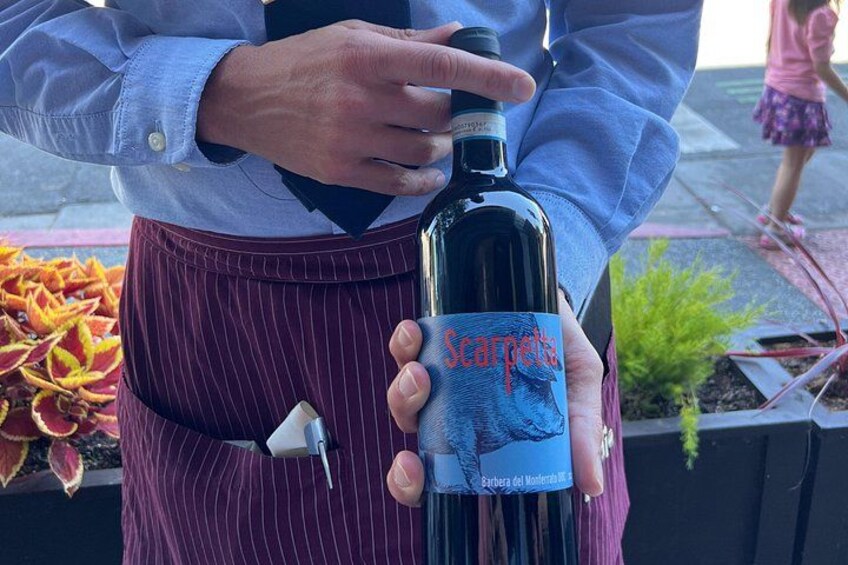 A person holding a bottle of Scarpone wine. 4