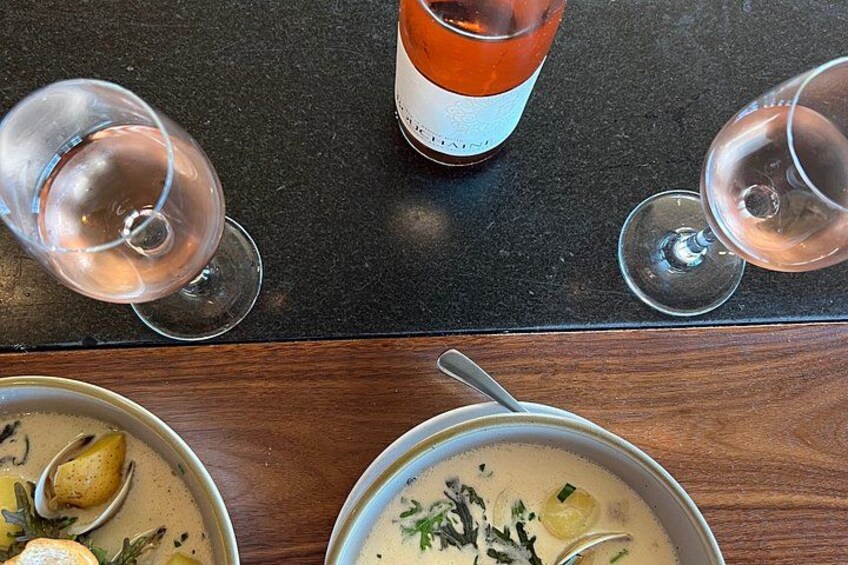 A table with a bottle of wine, two glasses of wine, and two bowls of soup. 5