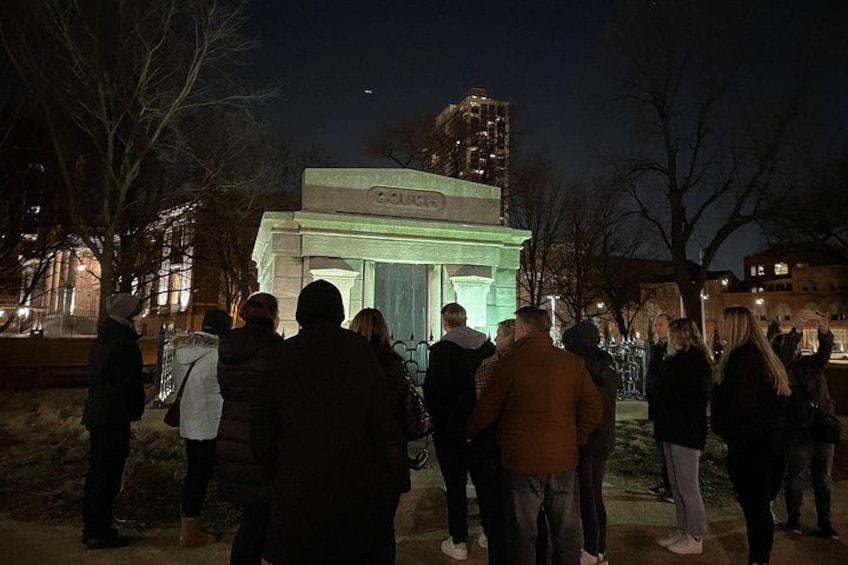 En gruppe mennesker samlet omkring et oplyst monument om natten. 1