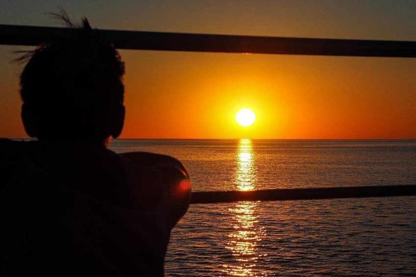 A silhouette of a person facing a sunset over the ocean. 2