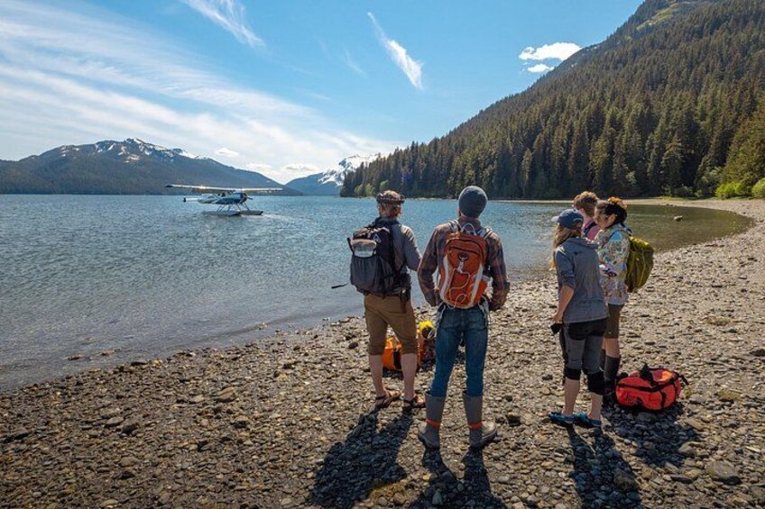 Un groupe de personnes se trouve sur une côte rocheuse, avec un lac et des montagnes en arrière-plan. 2
