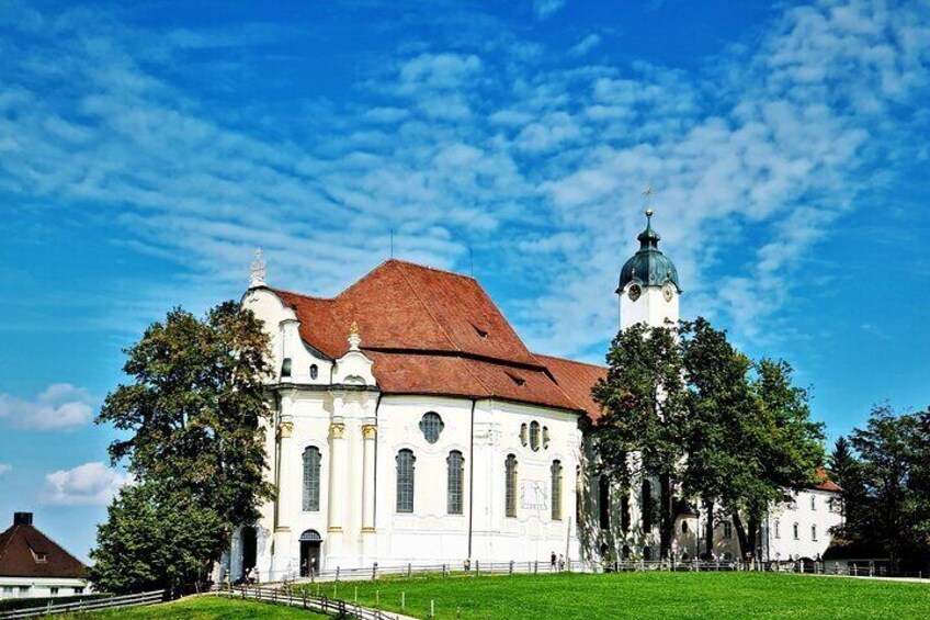 A white church with a red roof and a tower, surrounded by trees. 2