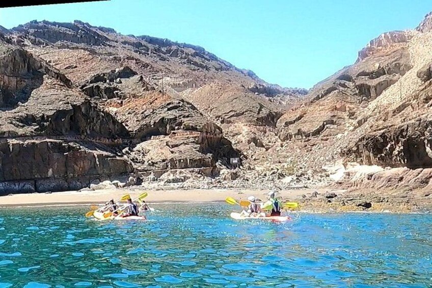 Un grupo de personas haciendo kayak en un río tranquilo rodeado de acantilados rocosos. 3