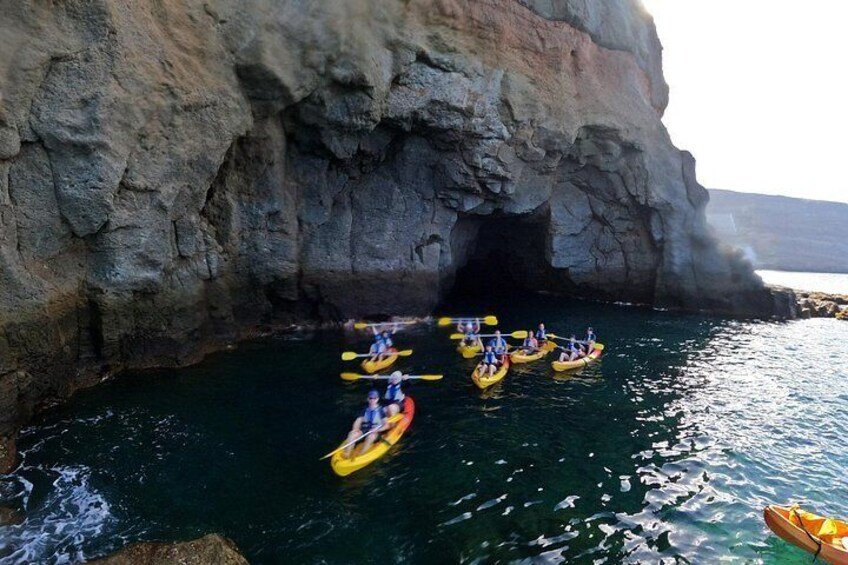 A group of people kayaking in a narrow waterway between rocky cliffs. 5