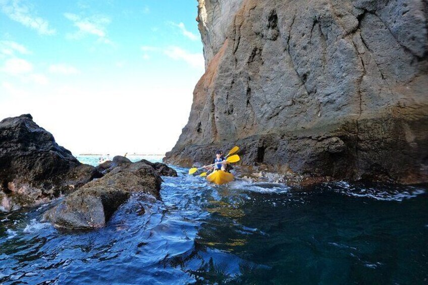 A kayaker navigating through a narrow waterway between large rocks. 2
