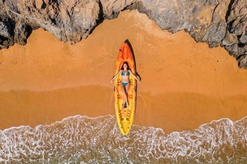 A person in a kayak on a sandy beach with waves. 2