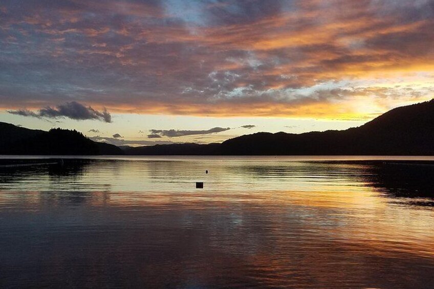 Un lac paisible au coucher du soleil, avec une petite bouée au centre et des collines en arrière-plan. 2