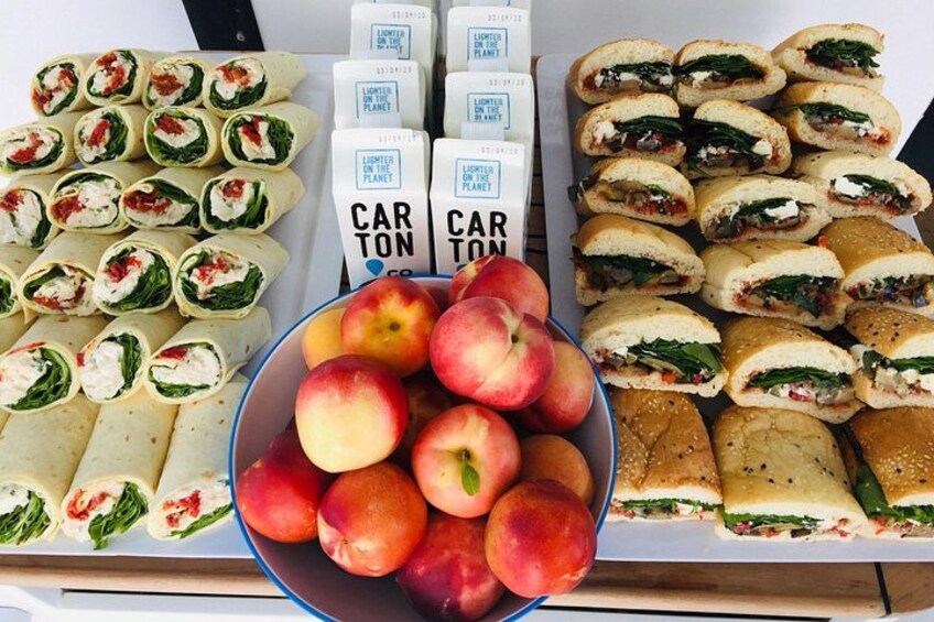A variety of food items including sandwiches, pastries, and a bowl of peaches. 2