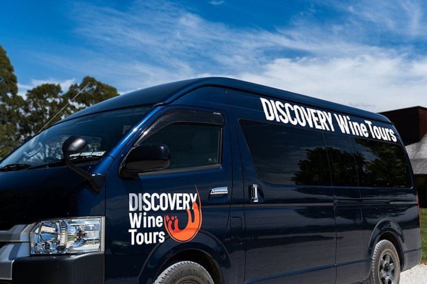 Una furgoneta azul oscuro con la leyenda 'DISCOVERY Wine Tours' escrita en la carrocería. 3