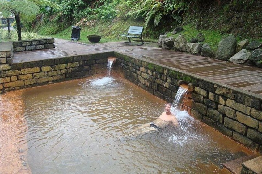 A hot spring with a wooden deck and stone walls. 1