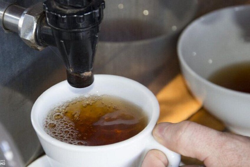 A hand holding a white cup under a coffee machine dispensing hot liquid. 5