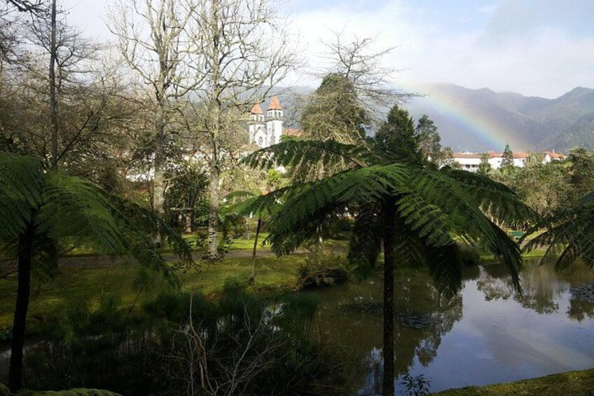 A serene landscape with a pond, lush greenery, and a building with a red roof in the background. 4