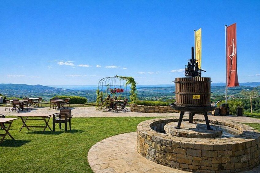 An outdoor dining area with tables and chairs, a stone fountain, and flags. 2