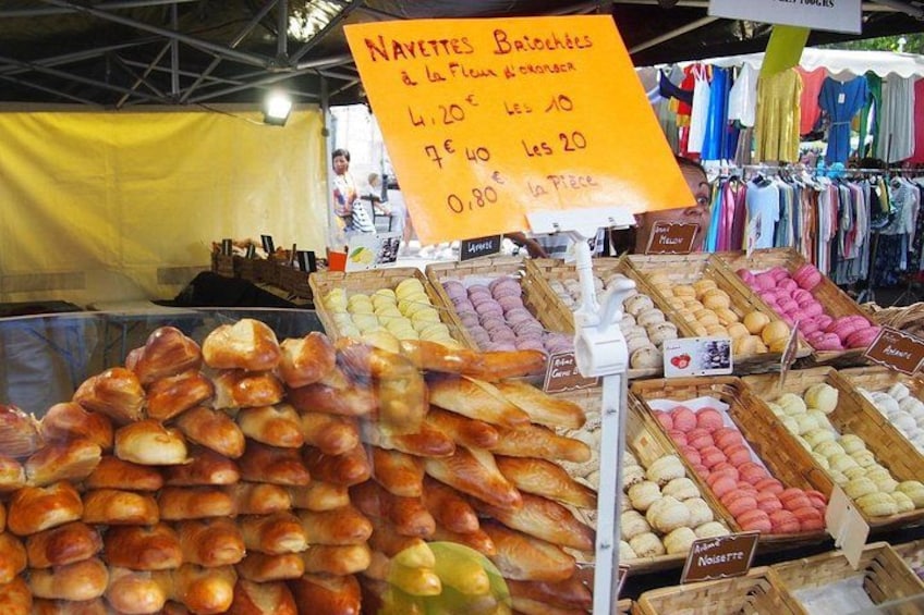 A market stall with various baked goods, including bread and pastries, with price tags visible. 4