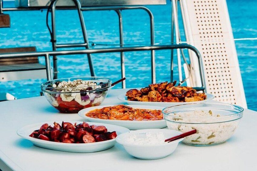 A table with various dishes including a salad, grilled chicken, and rice, by a poolside. 5
