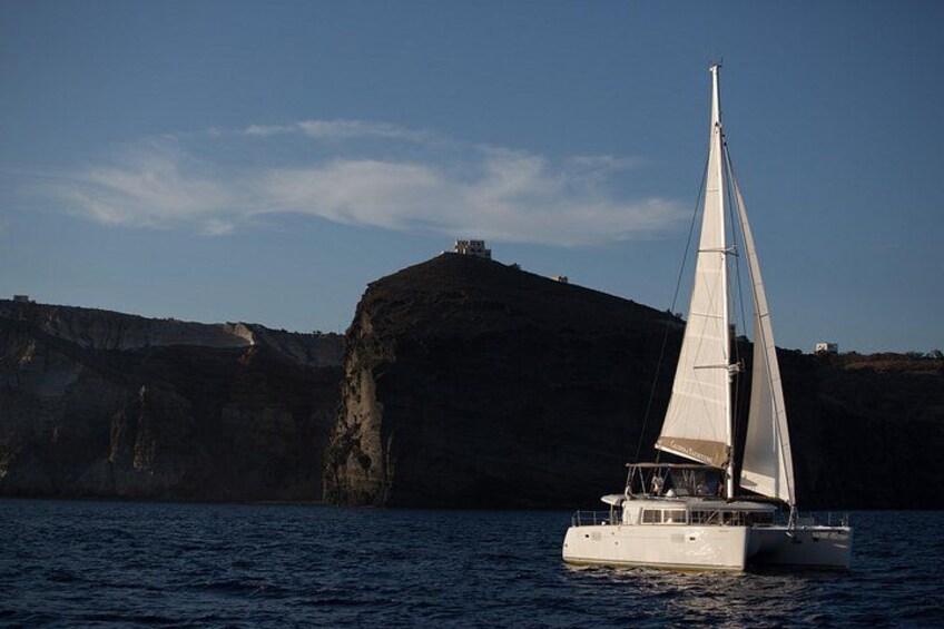 A sailboat on calm water with a rocky coastline in the background. 3