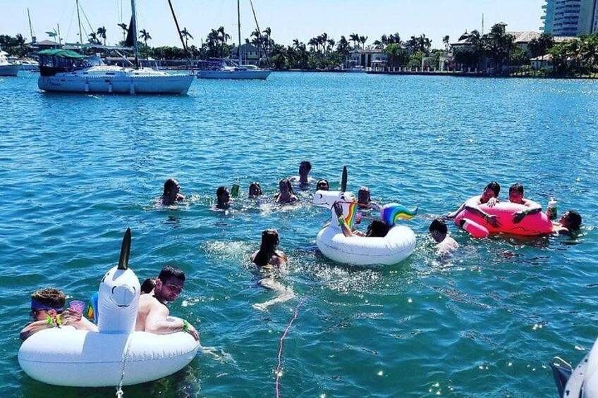 People floating on water with inflatable rings, boats in the background, and a clear sky. 4