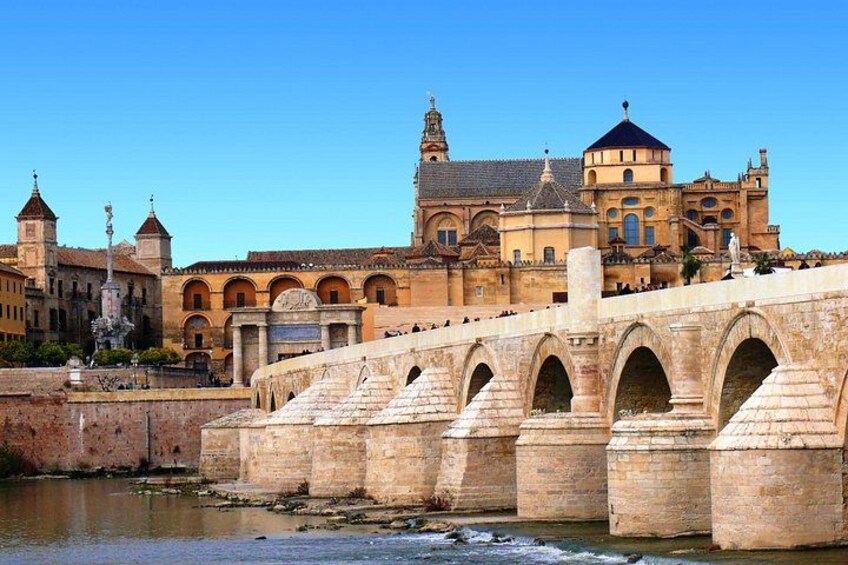 A stone bridge with arches, a river, and historic buildings in the background. 4