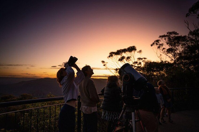 A group of people observing a sunset with a telescope. 4